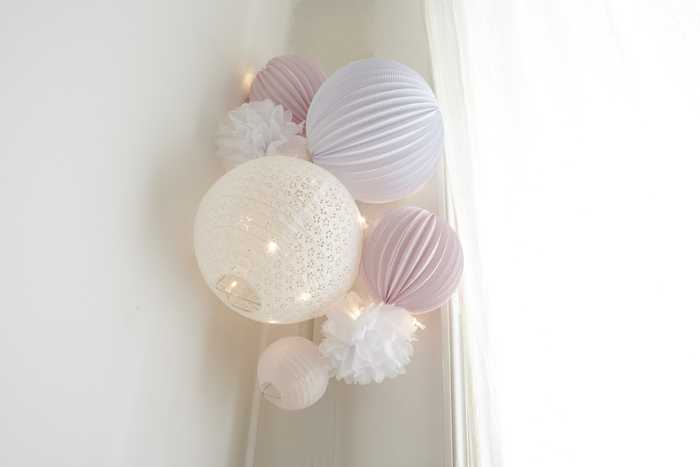 déco blanche et rose pâle pour une chambre de petite fille avec des lanternes et pompons