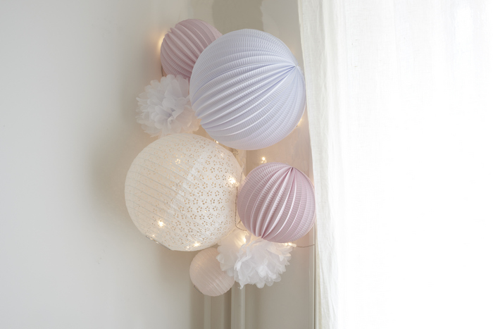 déco blanche et rose pâle pour une chambre de petite fille avec des lanternes et pompons